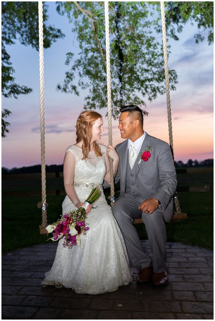 bride and groom on a swing at sunset