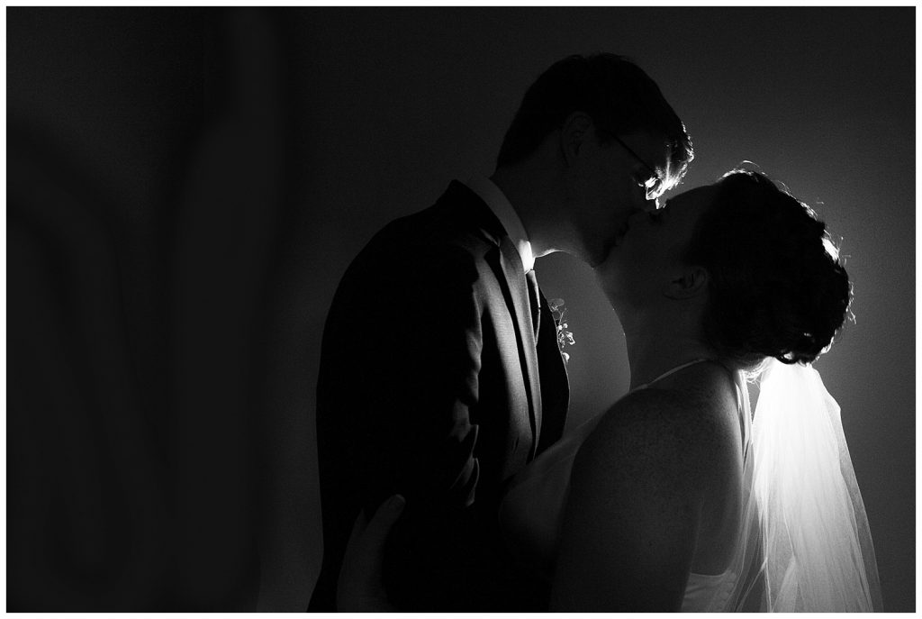 Dark and moody photo of the bride and groom kissing