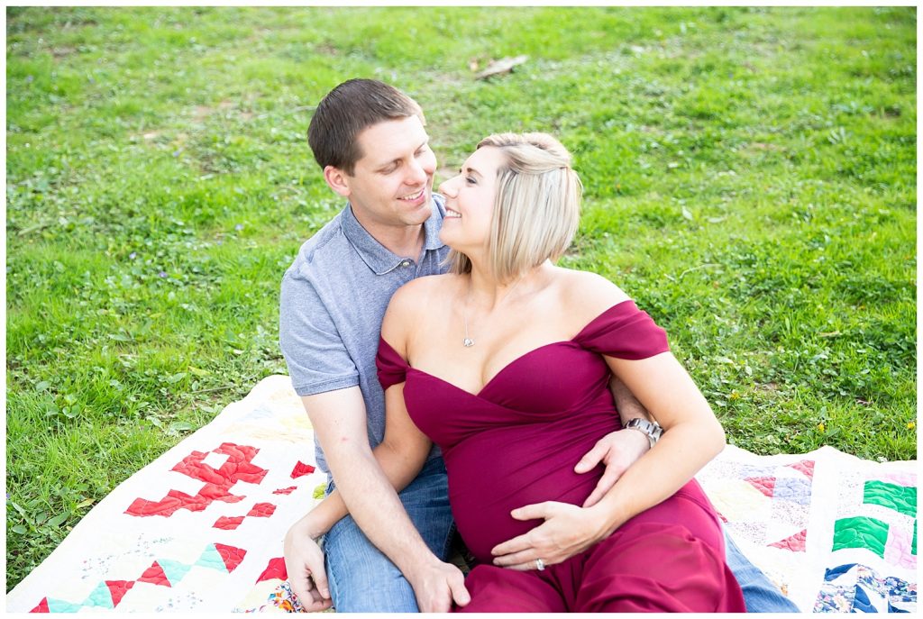 pregnant woman and man sitting on blanket