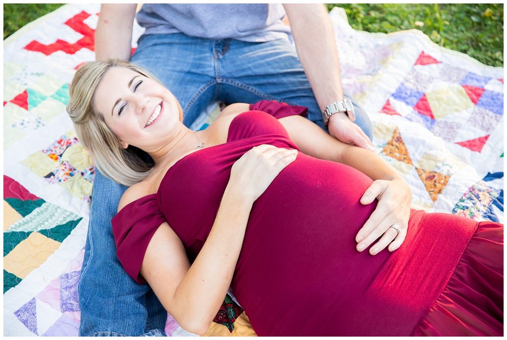 pregnant woman in red laying down and laughing