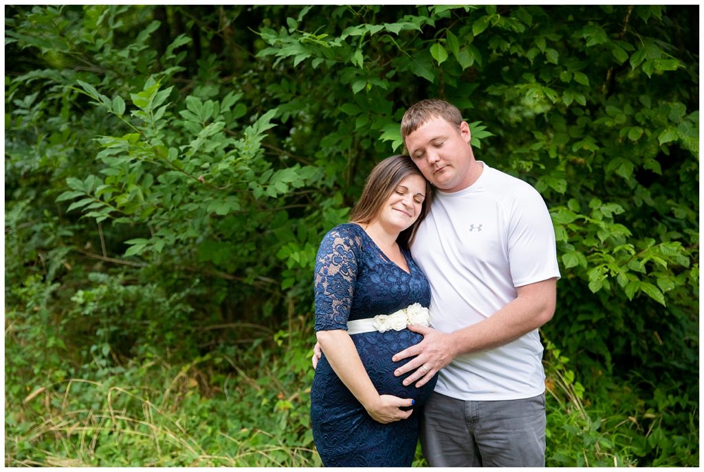 mom and dad with eyes closed touching pregnant belly