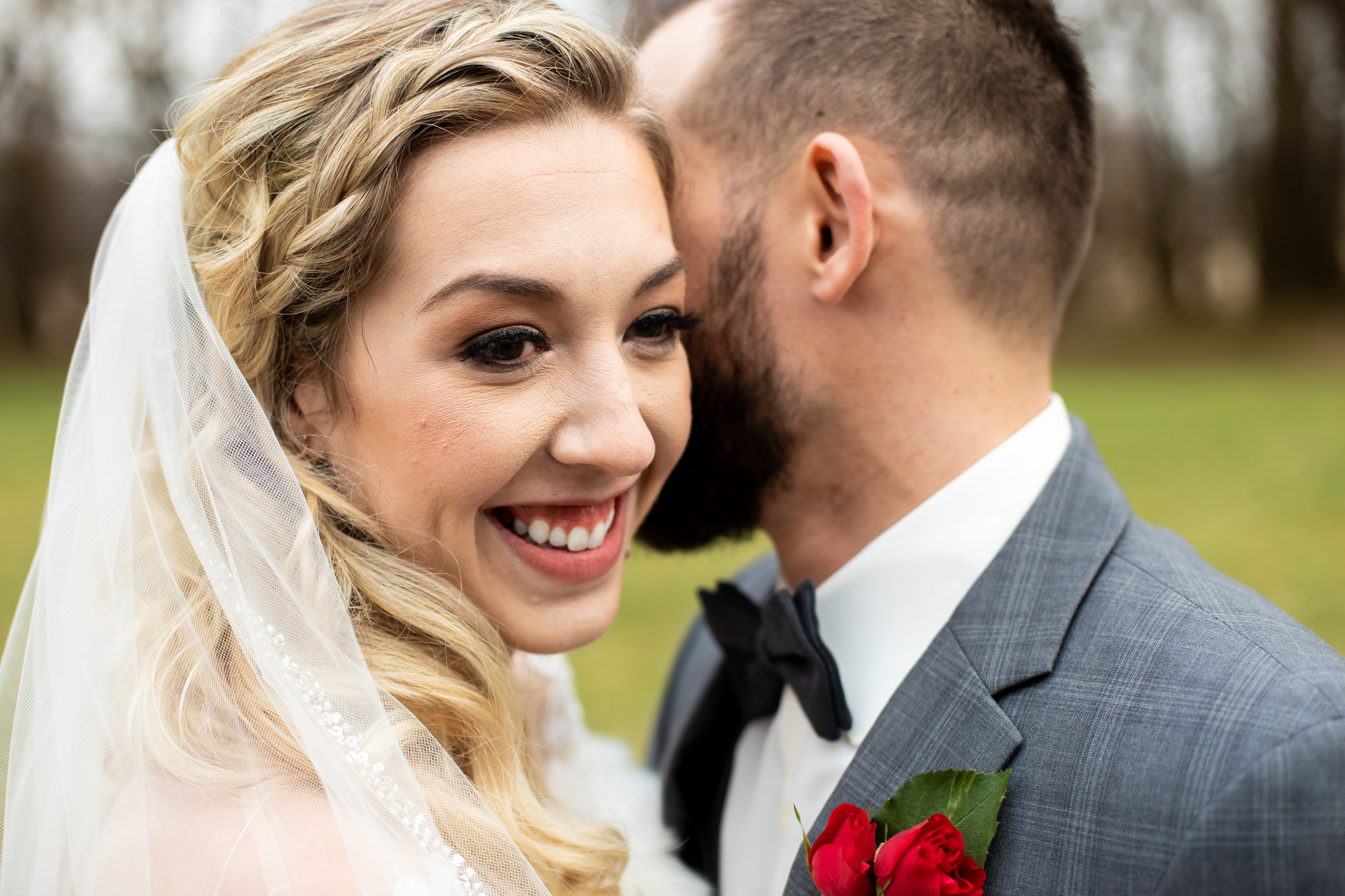bride smiling while groom whispers in her ear