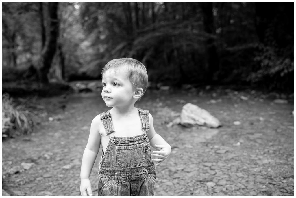 black and white photo of little boy in a creek