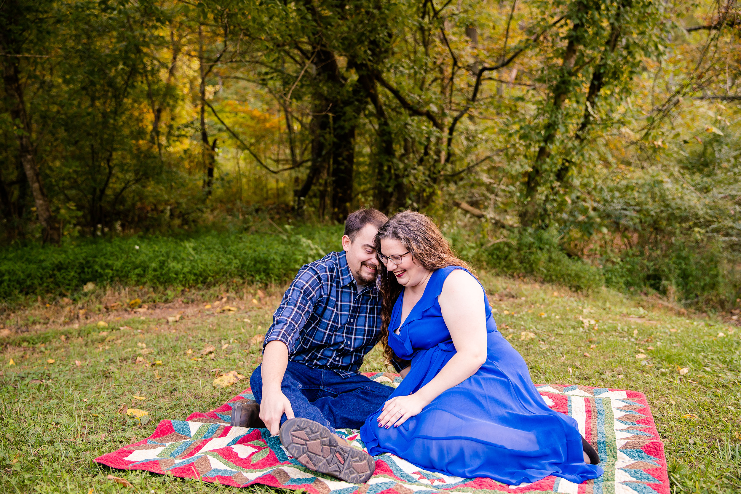 A couple sitting on a quilt laughing at Rotary Park in Clarksville, TN