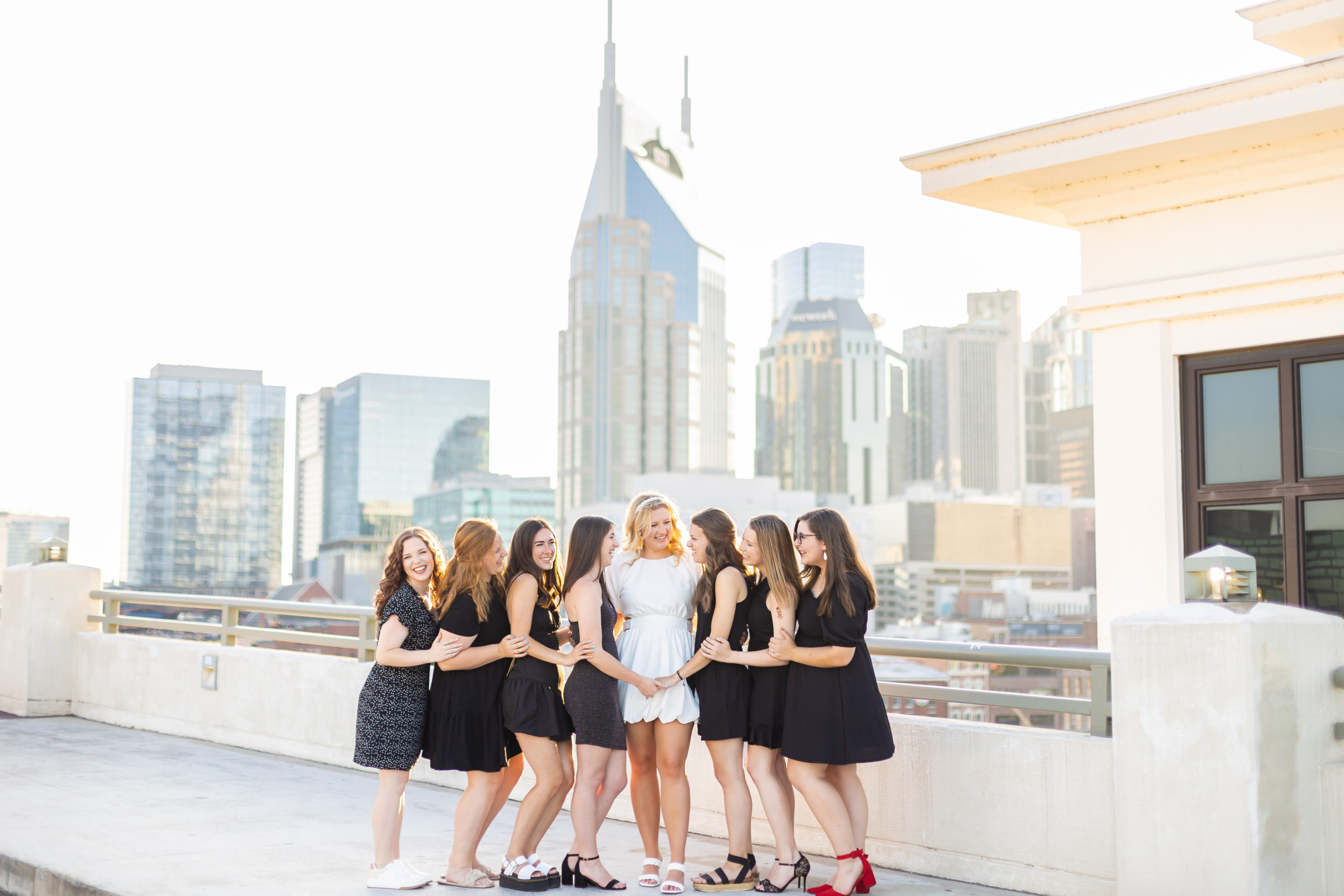 A bride smiling with her bridesmaids on the Pedestrian bridge in downtown Nashville, TN on her bachelorette party weekend.