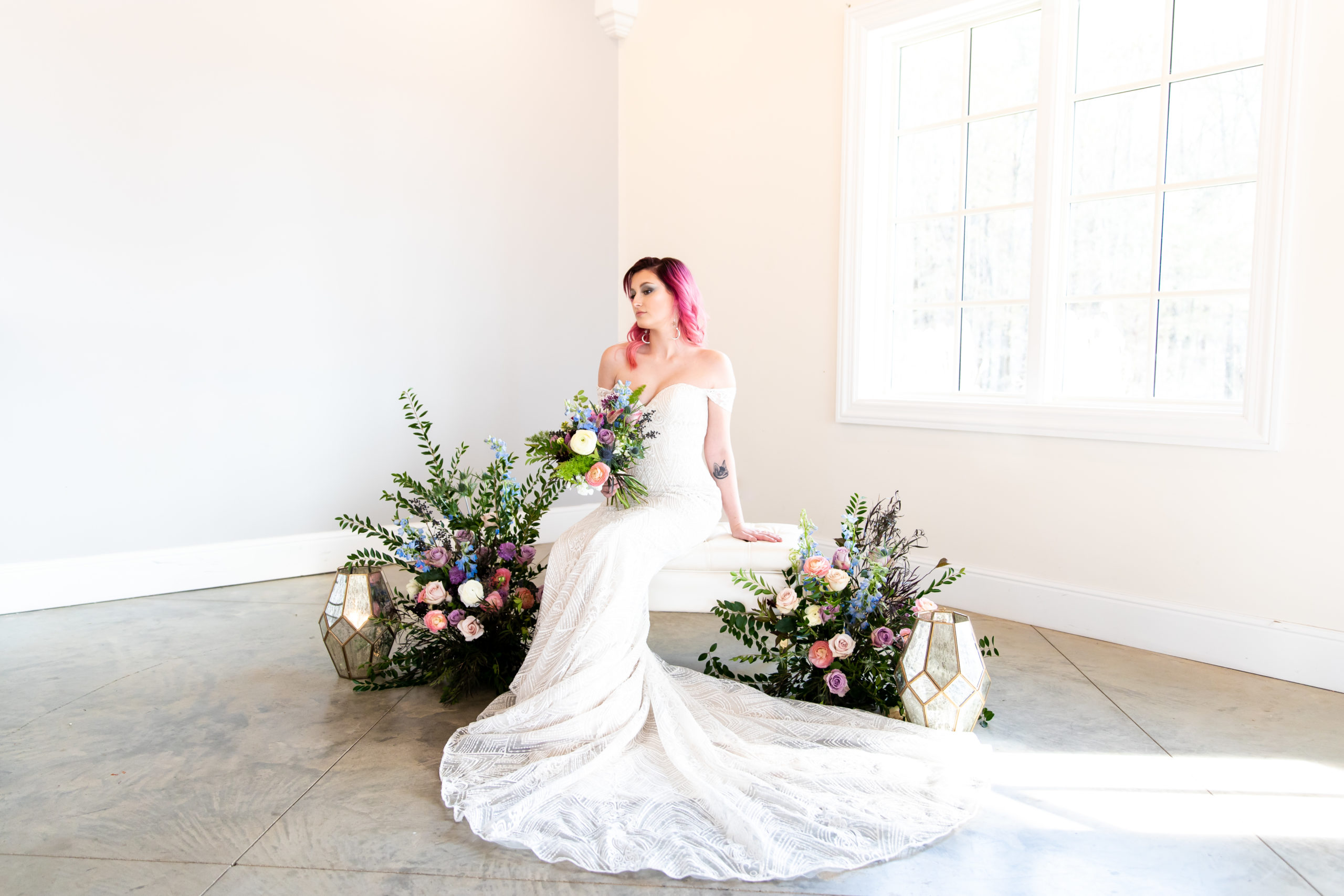 bride sitting in white room with colorful wedding flowers
