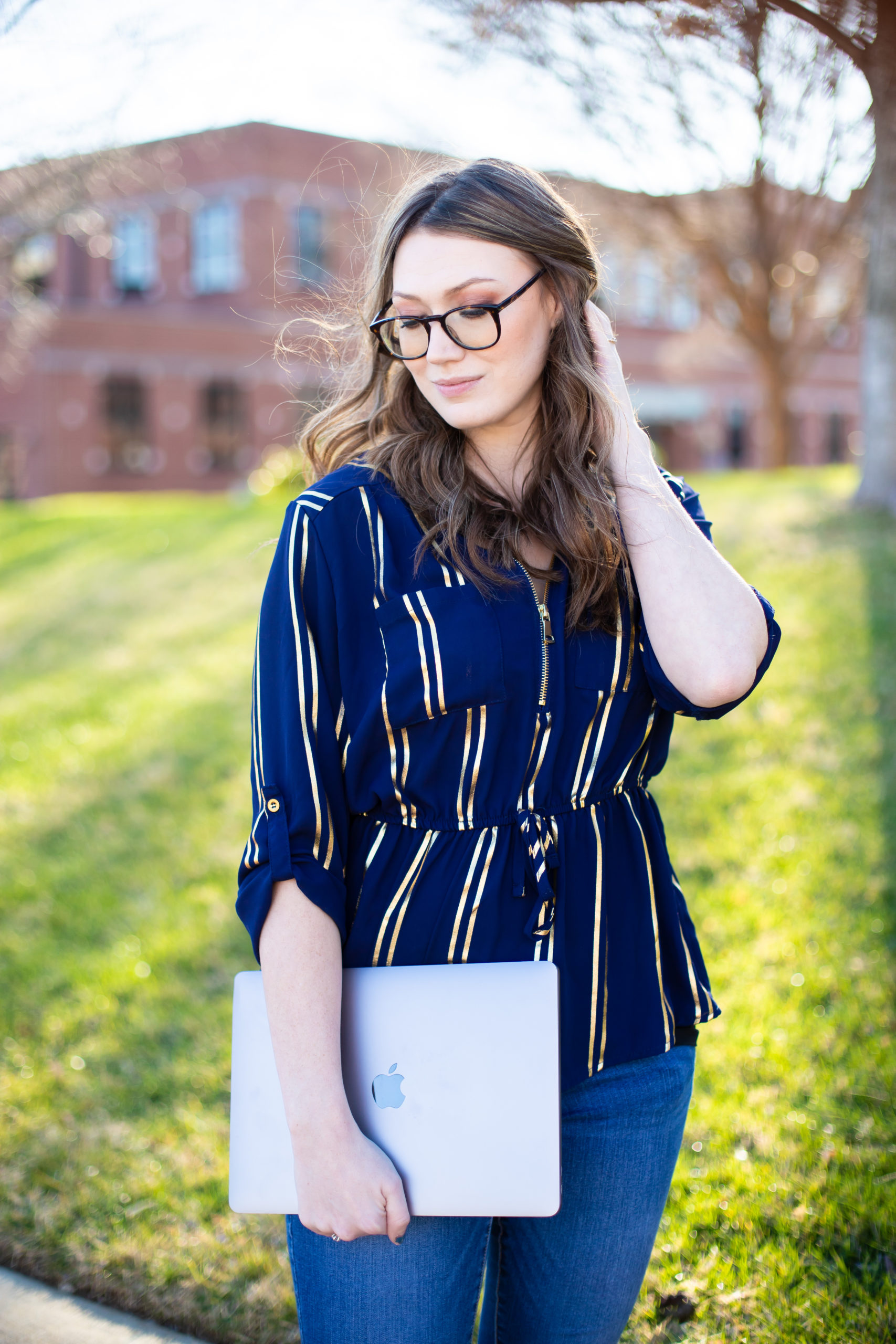 woman in glasses holding laptop outside