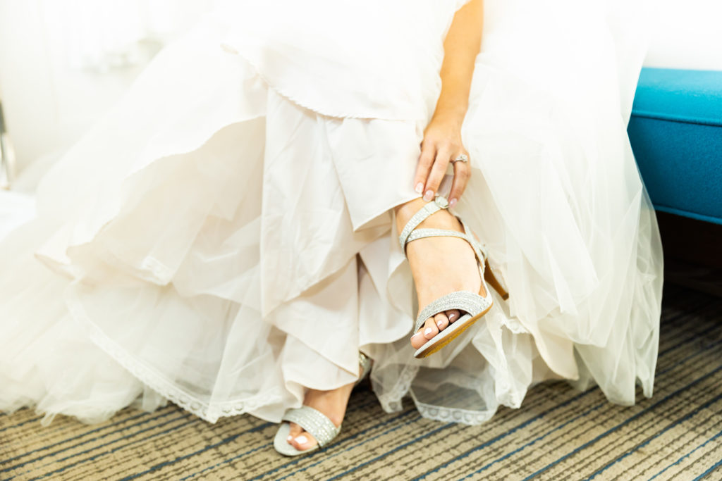bride putting on wedding shoes in wedding dress