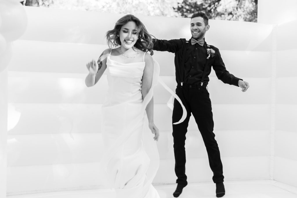 Bride and groom jumping in bounce house 