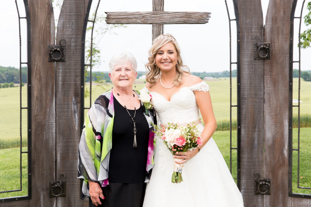 A bride smiles with her grandmother during family formals on her wedding day.