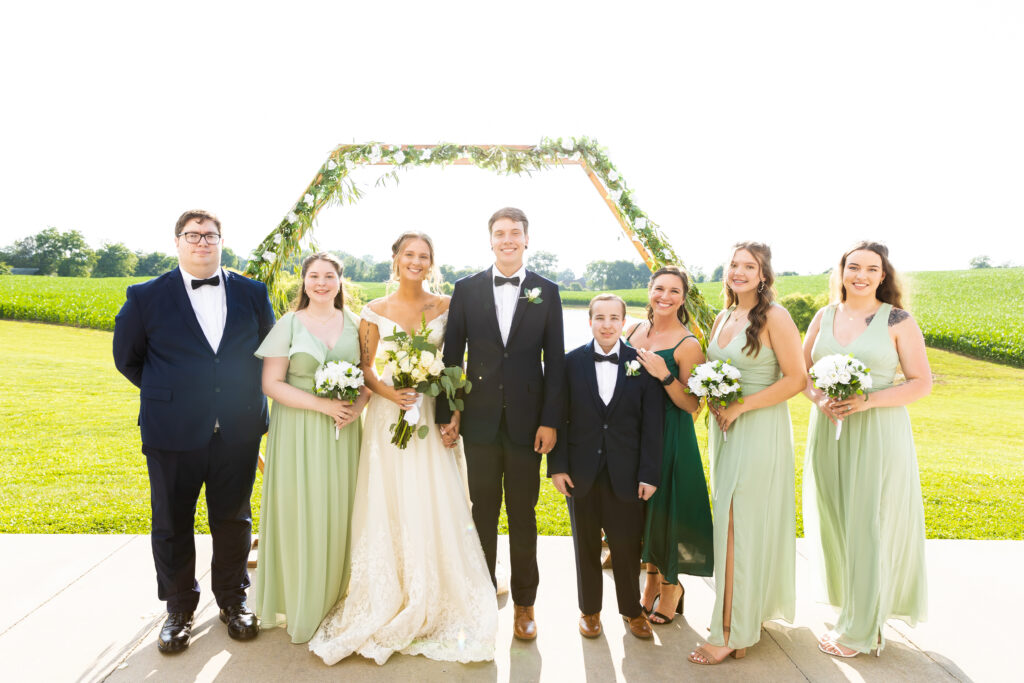 A bride and groom smile with their family in front of their altar.